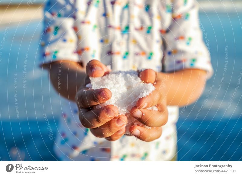 Ein kleiner Junge hält Salzkristalle in seinen Händen in Salinen in Faro, Algarve, Portugal Kristalle Industrie Inszenierung Kind abschließen Hand Menschen