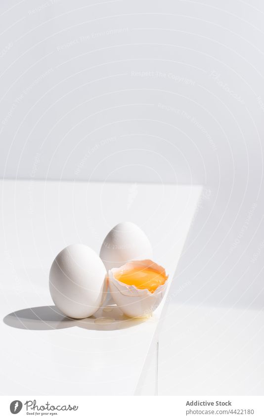Ganze und zerbrochene Hühnereier auf weißem Tisch Ei gebrochen Eigelb ganz sehr wenige Farbe Atelier einfach Ostern Feiertag frisch natürlich Stil Lebensmittel