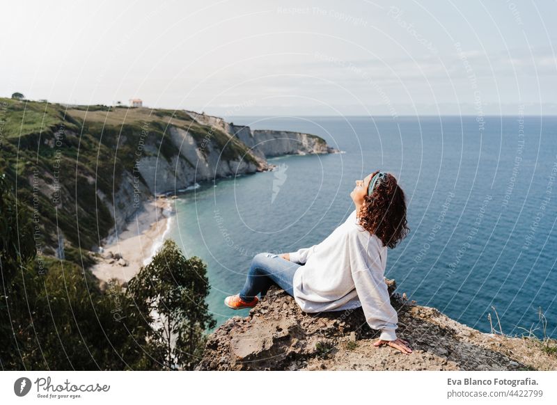 entspannte Frau sitzt auf der Spitze der Klippe mit Blick auf das Meer Landschaft in Asturien. Entspannen und Natur Konzept Kaukasier entspannend Klippen