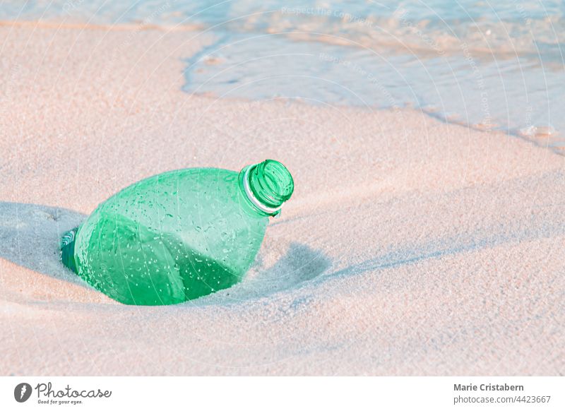 Nahaufnahme einer grünen Plastikwasserflasche, die im Sand vergraben ist plastische Verschmutzung Meeresverschmutzung Einwegplastik Umweltaktivismus Aktivismus