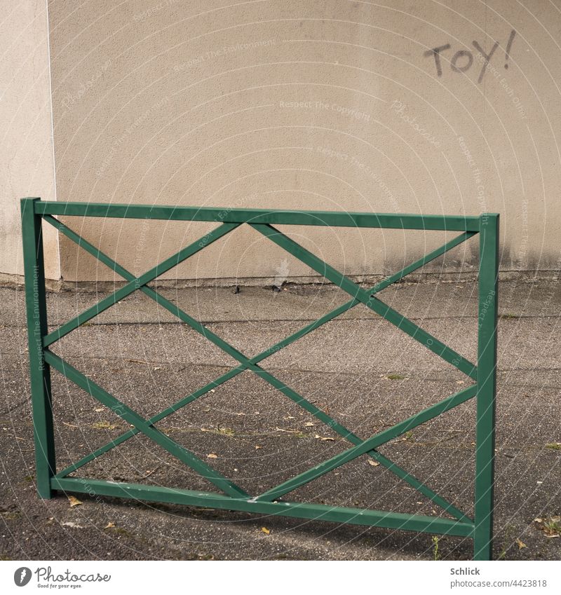 Toy mit Ausrufungszeichen steht an eine Wand geschrieben Text Schrift Bürgersteig Geländer Graffiti Asphalt grün grau beige Textfreiraum niemand menschenleer