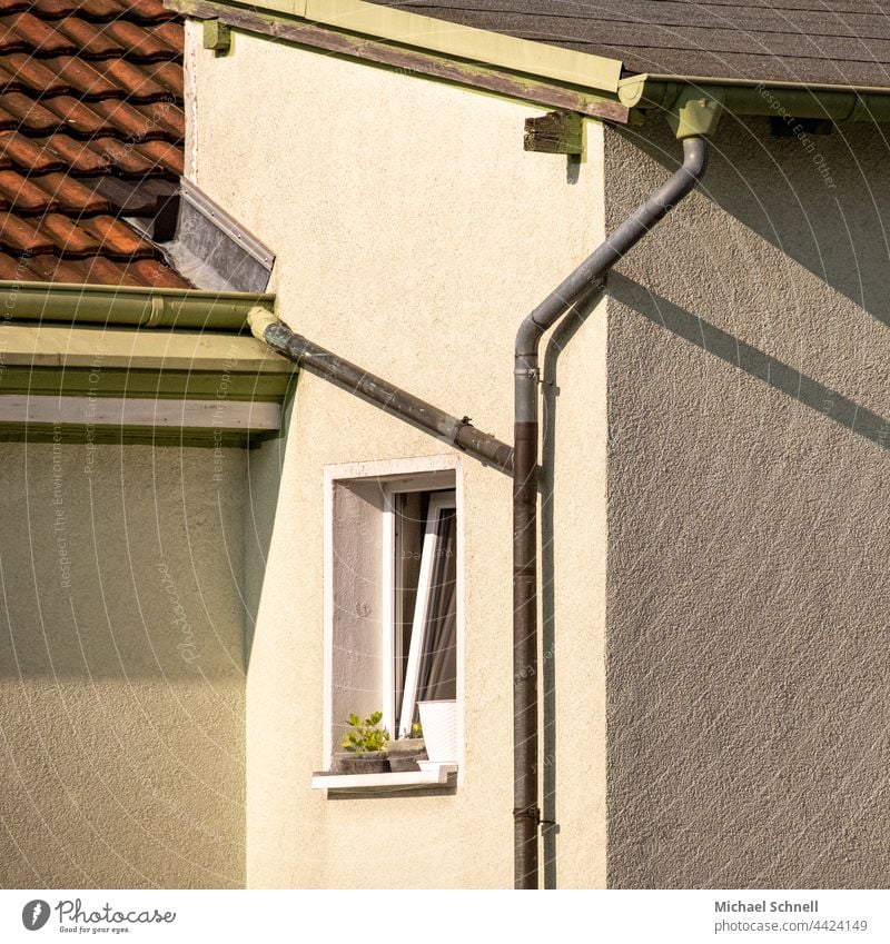 Fassadenausschnitt mit kleinem Fenster, Dächern, Wasserrohren und Schattenwürfe Hausfront Wand Außenwand Wohnhaus Menschenleer Mauer Stadt mietshaus Rohr