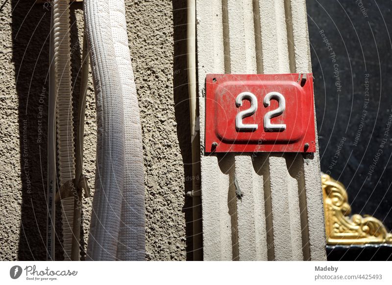Hausnummer 22 als Blechschild in Weiß auf Rot an einem alten Haus bei Sonnenschein in Taksim in Istanbul am Bosporus in der Türkei Zweiundzwanzig Schild Straße