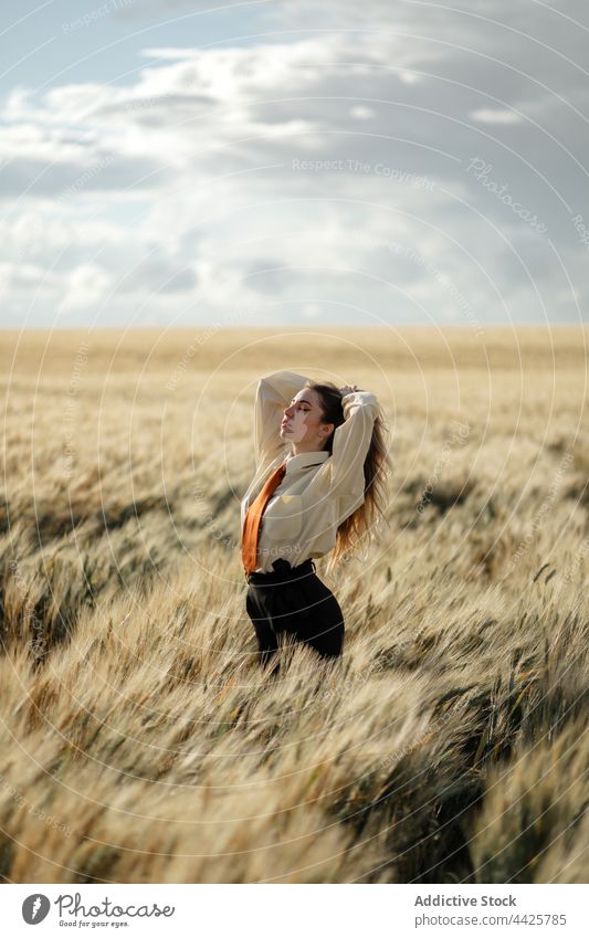Stilvolles Modell im Weizenfeld unter bewölktem Himmel Achtsamkeit Natur Spitze Feld Augen geschlossen wolkig Frau Landschaft Krawatte eingedenk verträumt