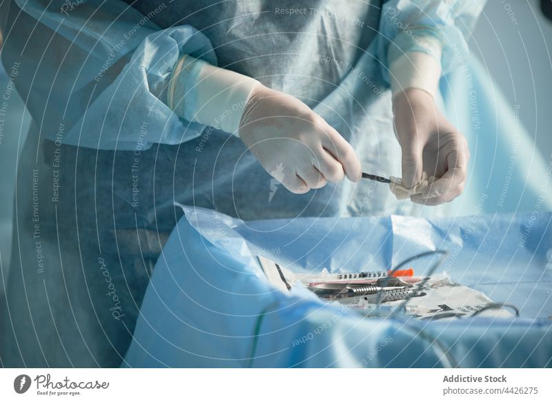 Eine Krankenschwester reinigt eine Spritze mit einem Tuch im Operationssaal Chirurg Sauberkeit Krankenpfleger Wischen desinfizieren steril Uniform vorbereiten