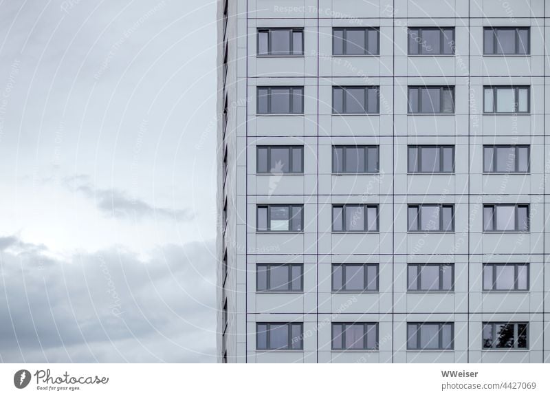 Ein Wohnhaus mit anonymen Fenstern vor leicht bewölktem Abendhimmel Wohnheim Studentenwohnheim Haus Gebäude gleich trist grau Himmel Fassade Wolken Architektur