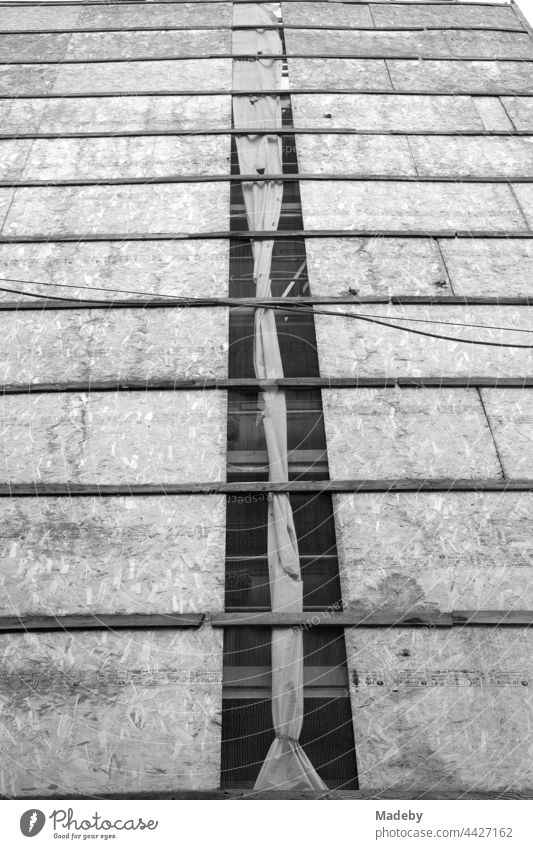 Fassadenverkleidung aus Spanplatten und alte Stromkabel vor der Fassade eines Altbau im Galataviertel im Stadtteil Beyoğlu in Istanbul am Bosporus in der Türkei, fotografiert in klassischem Schwarzweiß