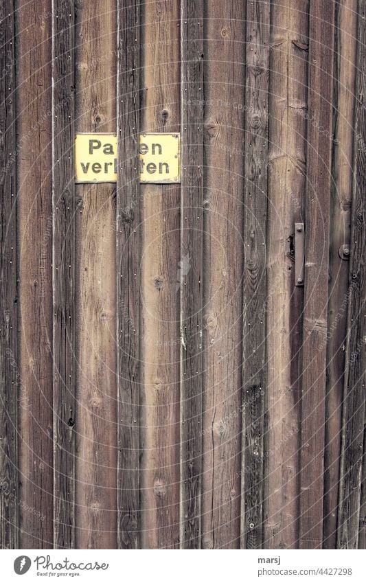 Parken verboten könnte das Schild auf dem Holztor heißen. Hinweisschild Tor Tür Wand Mauer verwittert Verbote Parkverbot Warnschild außergewöhnlich alt Patina