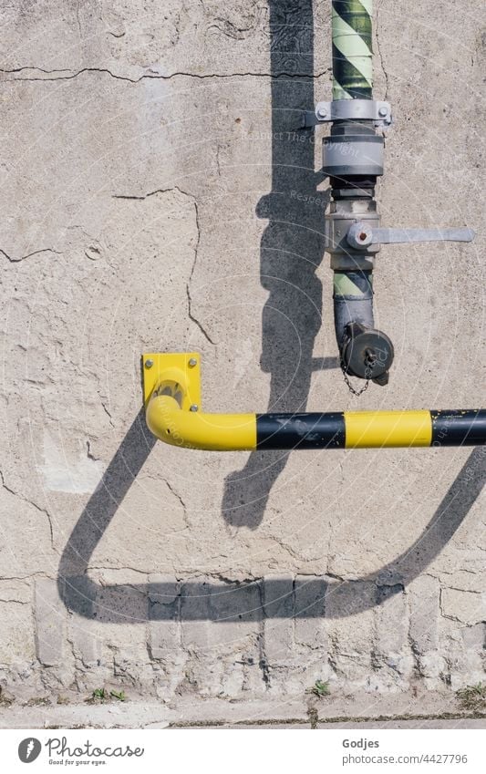 Rohr einer Pumpstation und Sicherheitsbügel in Gelbschwarz an einer Betonwand. Rohrleitung Schöpfwerk Menschenleer Außenaufnahme Röhren Wand Farbfoto Mauer