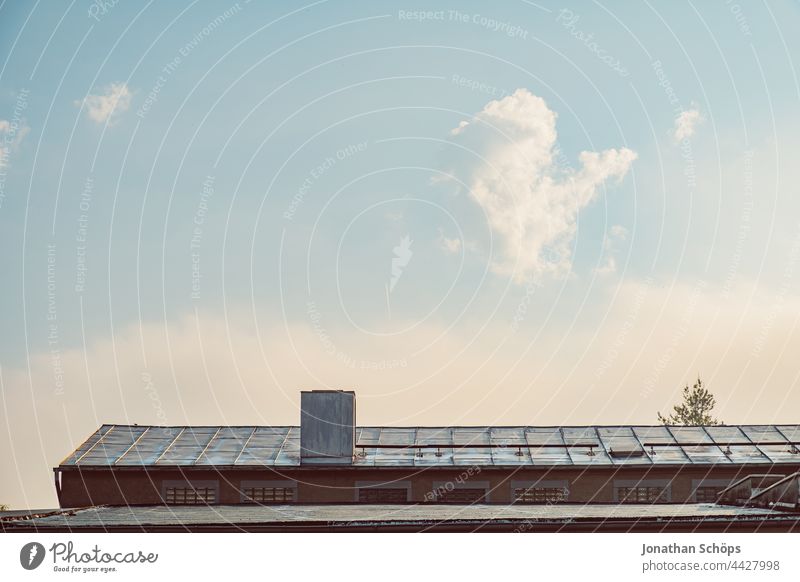 weiter Himmel über Hausdach Lagerhalle Gebäude Dach Halle Schornstein Industriegebiet Morgensonne sonnig Wolken Textfreiraum himmelblau minimalistisch leer