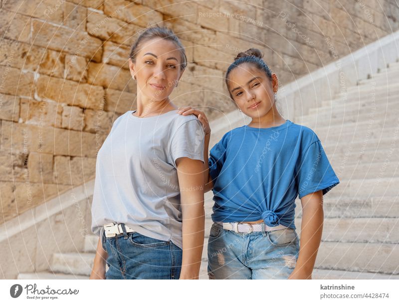 Mutter und Tochter stehen auf einer Steintreppe im Freien Kind Treppe Mädchen Attrappe mittleren Alters Frau Schulkind tragend T-Shirts Umarmen Mama