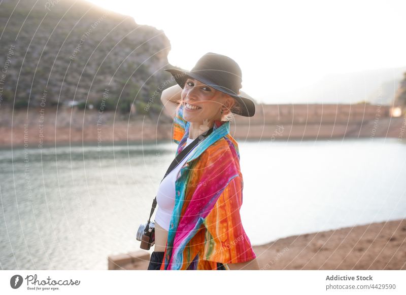 Frau mit schwarzem Hut in einem See und einer Fotokamera in der Hand Tourist cool Stil Natur Ufer Baum Reflexion & Spiegelung Urlaub Reisender lässig Bekleidung