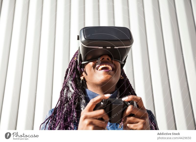 Schwarze Frau spielt VR-Spiel Headset Regler Erfahrung aufgeregt Virtuelle Realität Schutzbrille spielen jung Afroamerikaner schwarz ethnisch Afro-Look genießen
