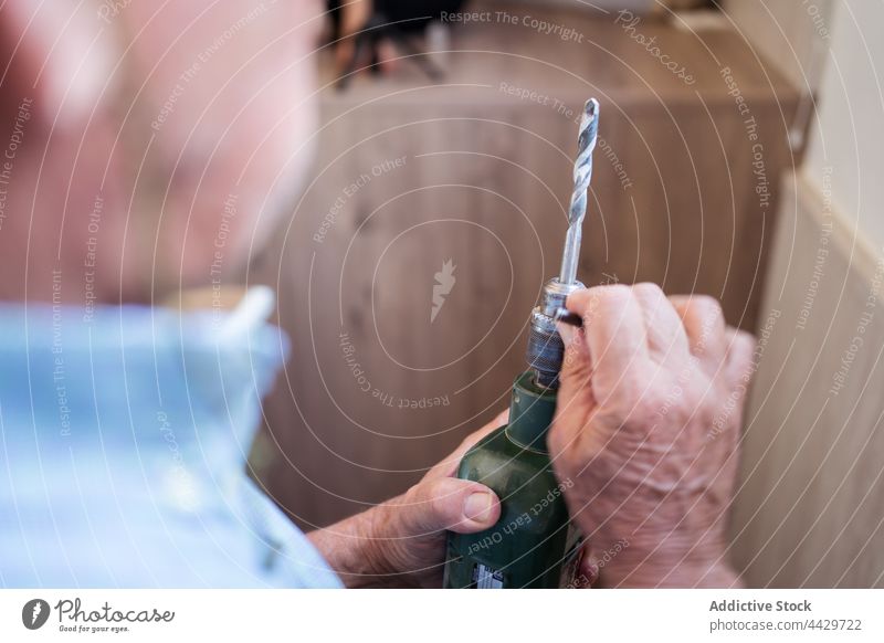 Alter Mann, der eine Düse an einem elektrischen Schraubenzieher befestigt Tülle Schraubendreher Kraft diy vorbereiten Gerät fixieren Haus Raum Metall Material