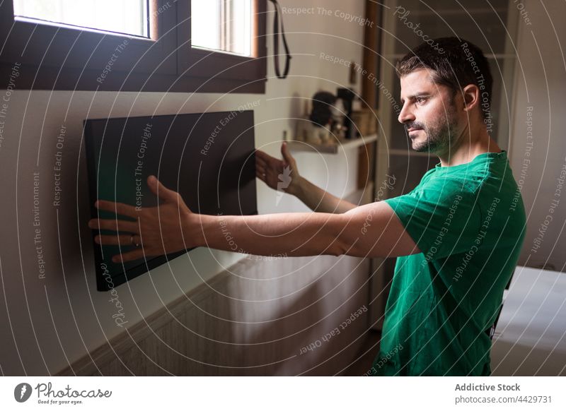 Mann bei der Installation eines Monitors an der Wand zu Hause installieren ausrichten Computer schwarzer Bildschirm diy Genauigkeit Fokus heimwärts