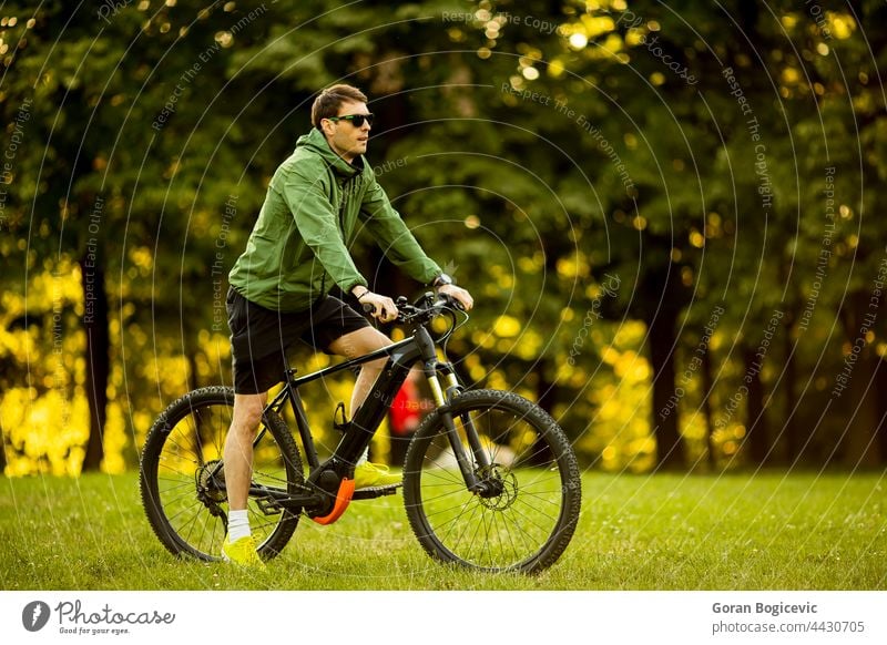 Junger Mann fährt E-Bike im Park aktiv Batterie Fahrrad Biker Radfahren schwarz Zyklus Radfahrer ebike Öko ökologisch Ökologie elektrisch Elektro Energie Motor