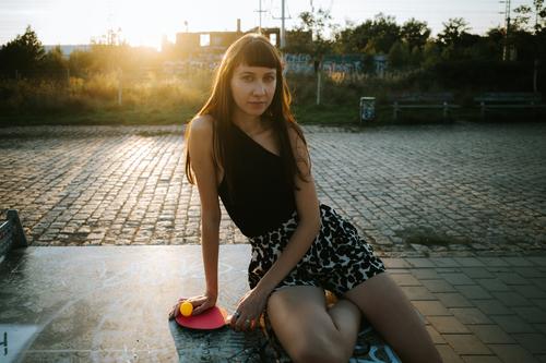stilvolle kaukasische Frau lehnt sich an eine Tischtennisplatte aktiver Lebensstil schön Freizeitkleidung kaukasische Ethnizität Abend Hüfte Hipster menschlich