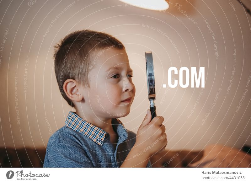 Kind schaut durch ein Vergrößerungsglas, sieht auf einer Website nach, surft im Internet .com Analysieren Browsen Business Kaukasier Detailaufnahme Detektiv