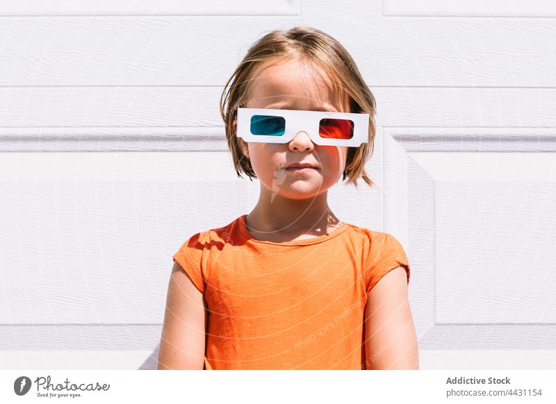 Trendiges Kind mit 3D-Brille an der Wand stehend dreidimensional unterhalten 3d Spaß Freude lässig Mädchen zuschauen Film Vorstellungskraft modern emotionslos