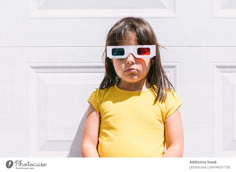 Trendiges Kind mit 3D-Brille an der Wand stehend dreidimensional unterhalten 3d Spaß Freude lässig Mädchen zuschauen Film Vorstellungskraft modern emotionslos
