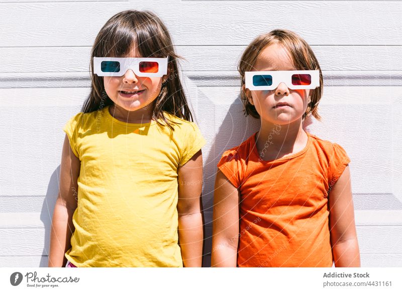 Glückliche trendige Kinder mit 3D-Brille an der Wand stehend dreidimensional unterhalten 3d Spaß Lächeln Showtime Freude lässig Mädchen zuschauen Film