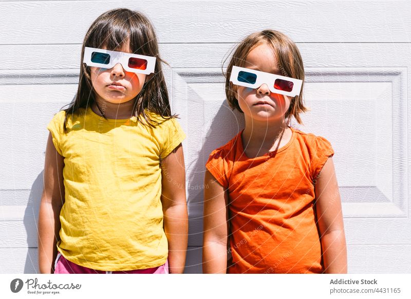 Trendige Kinder mit 3D-Brille an der Wand stehend dreidimensional unterhalten 3d Spaß Freude lässig Mädchen zuschauen Film Vorstellungskraft modern emotionslos
