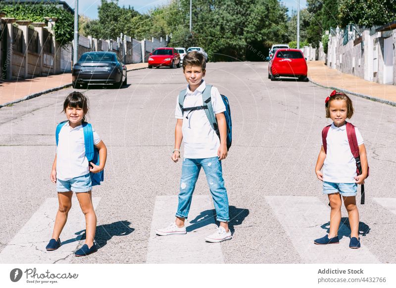 Schulkinder mit Rucksäcken auf dem Zebrastreifen in der Stadt Rucksack zurück zur Schule Arbeitsweg Freund Kindheit selbstbewusst lässig Stil Straße Junge