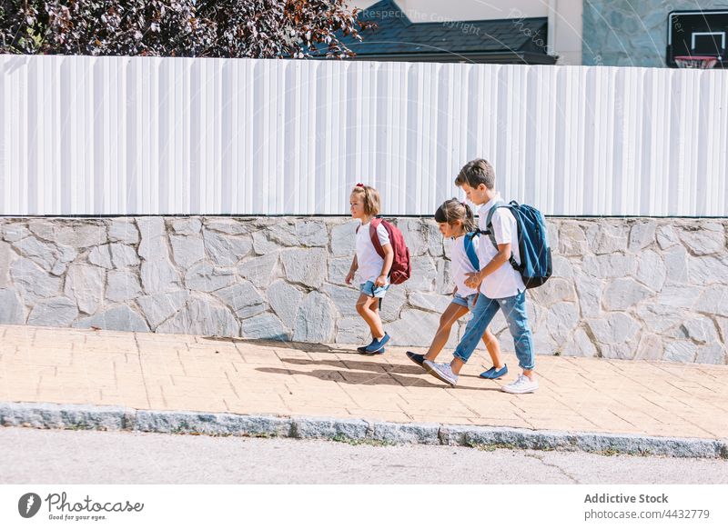 Schulkinder unterhalten sich beim Gehen auf dem Bürgersteig in der Stadt Jeansstoff Gespräch Freundschaft zurück zur Schule Kindheit sorgenfrei schlendern