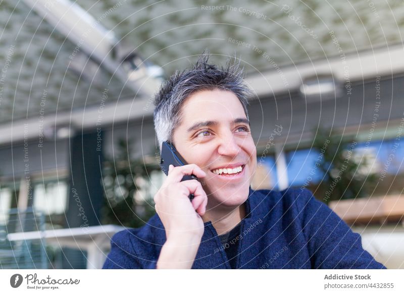 Fröhlicher Mann, der mit einem Handy spricht Smartphone reden männlich sprechen Lächeln Gespräch heiter Telefon Mobile Glück Anruf Telefonanruf Apparatur Straße