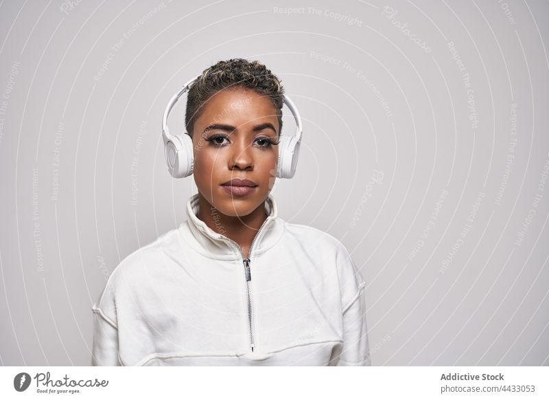 Schwarze Frau, die mit einem Kopfhörer Musik hört, steht auf grauem Hintergrund Choreographie Headset Energie Mode benutzend Apparatur aktiv Gerät Tänzer