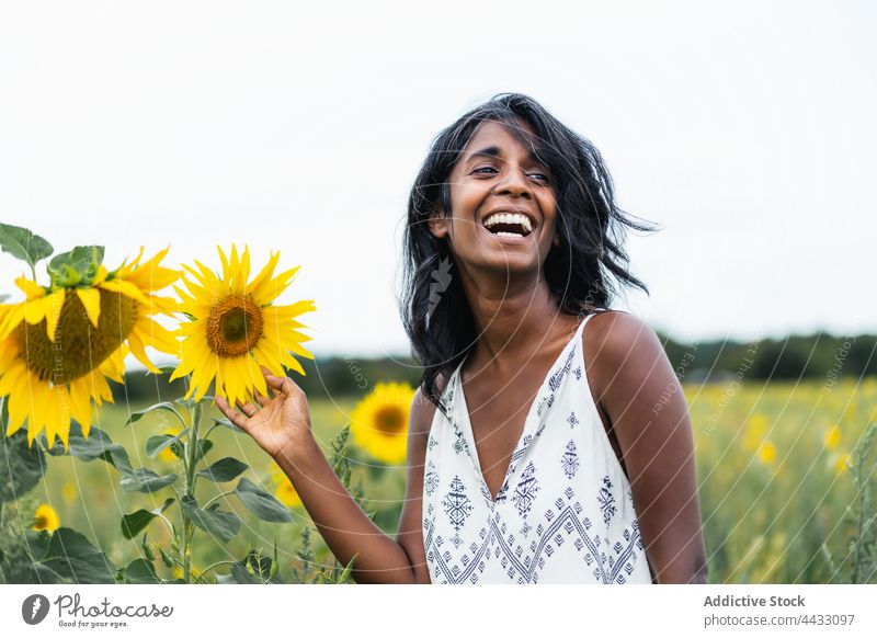 Lächelnde indische Frau in einem Feld mit blühenden Sonnenblumen herzlich sanft romantisch freundlich Landschaft Porträt Ornament Stoff geblümt Wiese Natur