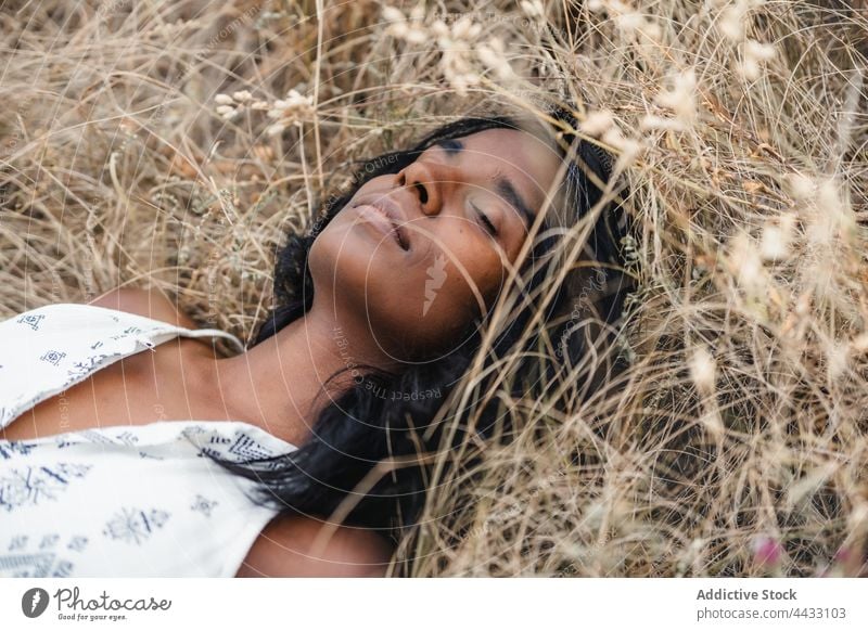 Konzentrierte indische Frau auf verblasstem Gras in der Landschaft ruhend Augen geschlossen Gelassenheit eingedenk Harmonie idyllisch natürlich ruhig