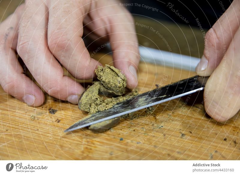 Crop Mann schneidet trockenes Marihuana Stück auf Schneidebrett geschnitten Cannabis Spielfigur Pflanze Kraut natürlich vorbereiten Arbeitsbereich cbd ganja