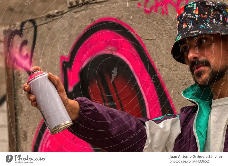 Graffitikünstler mit einer Sprühdose in der Hand, aus der rosa Farbe austritt Typ Mann jung Lifestyle Spray Anstreicher Kunst Künstler Kreativität kreativ