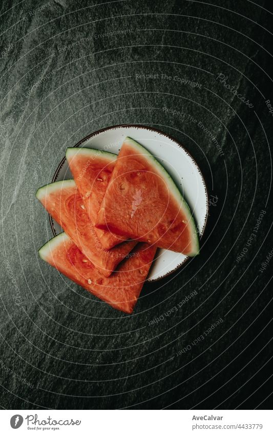 Luftaufnahme einer mit Wassermelone gefüllten Schale über einem schwarzen Marmortisch, frische Lebensmittel, Wellness, gesunde Ernährung Künstler Kirsche