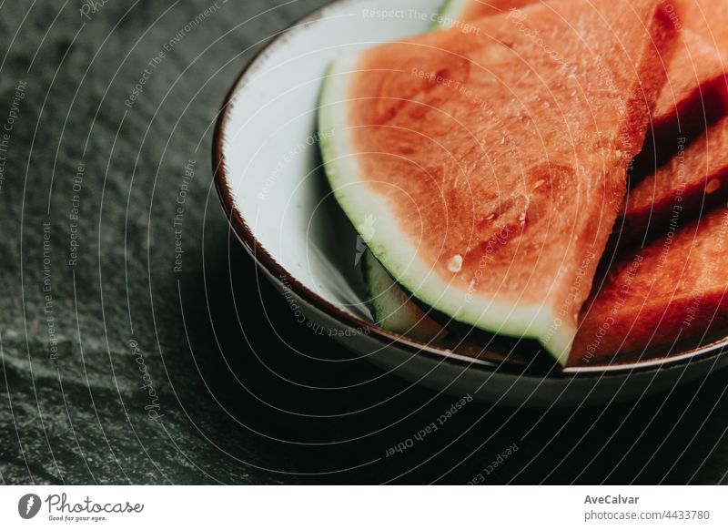 Nahaufnahme einer Schale mit Wassermelone über einem schwarzen Marmortisch, frische Lebensmittel, Wellness, gesunde Ernährung Künstler Kirsche Früchte