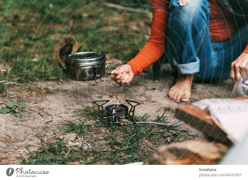Eine Frau kocht Essen mit einem tragbaren Gasbrenner im Wald Lebensmittel Brenner Aktivität Tourismus Lager im Freien Natur Abenteuer reisen Picknick wandern