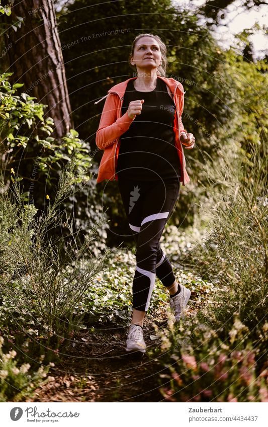 Sportliche Frau beim Jogging im Wald sportlich Natur Gesundheit Training Lifestyle Fitness Joggen laufen joggen Gegenlicht orange Sonne Heide schön stretching