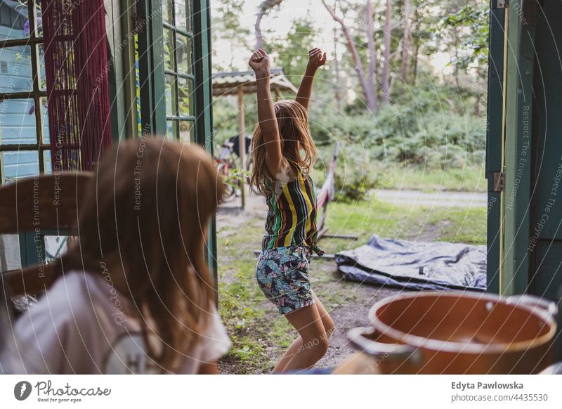 Spielende Kinder in der Gartenlaube Gartenhaus Cottage heimwärts Haus Hinterhof Tanzen spielerisch Freude Familie niedlich Mädchen wenig Glück Kindheit Spaß
