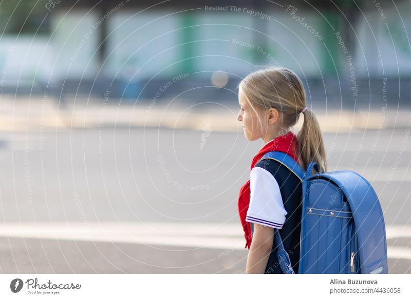 Zurück zur Schule. Kleines Mädchen aus der Grundschule im Freien auf Bushaltestelle. Kind geht neue Dinge zu lernen 1. september zurück zur Schule Öffentlich