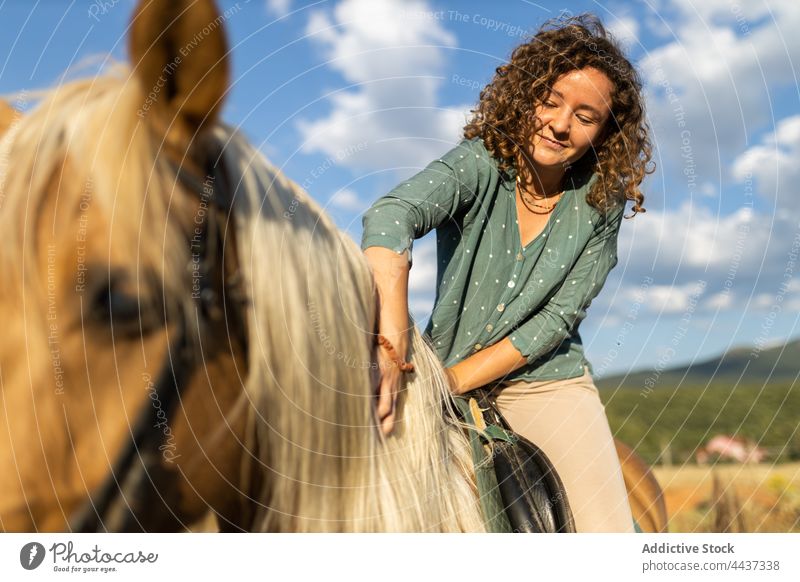 Frau auf Pferd in ländlicher Reitschule Pferderücken Stute Streicheln Mähne pferdeähnlich Tier Viehbestand Lächeln Landschaft domestiziert Hengst