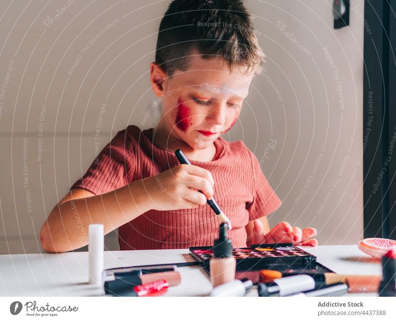 Junge trägt Lidschatten auf Gesicht in Haus Zimmer Make-up Applikator Schönheit Kosmetik dekorativ unordentlich Spaß haben Porträt Kindheit Palette Produkt