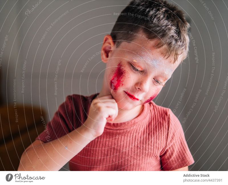 Schmutziger Junge mit Schminke auf den Wangen zu Hause unordentlich Kosmetik Make-up Schönheit dreckig Fokus Kindheit rote Lippen dekorativ achtsam freie Zeit