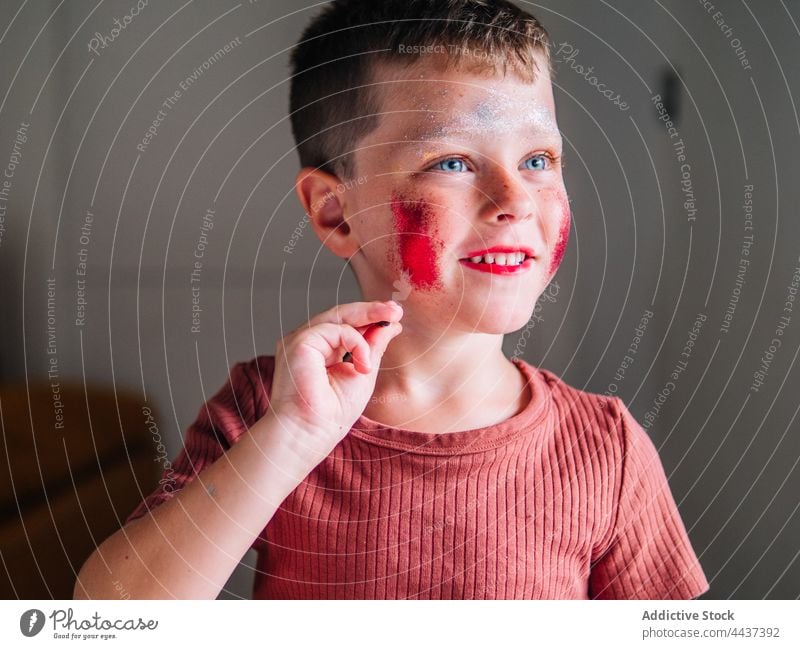 Schmutziger Junge mit Schminke auf den Wangen zu Hause unordentlich Kosmetik Make-up Schönheit dreckig Fokus Kindheit rote Lippen dekorativ achtsam freie Zeit