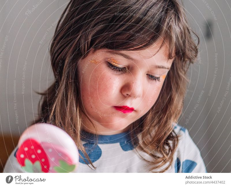 Mädchen trägt zu Hause Glitter auf das Gesicht auf Make-up bewerben Schönheit Kosmetik dekorativ Spiegel achtsam Kindheit Erdbeeren Ornament Fokus sortiert