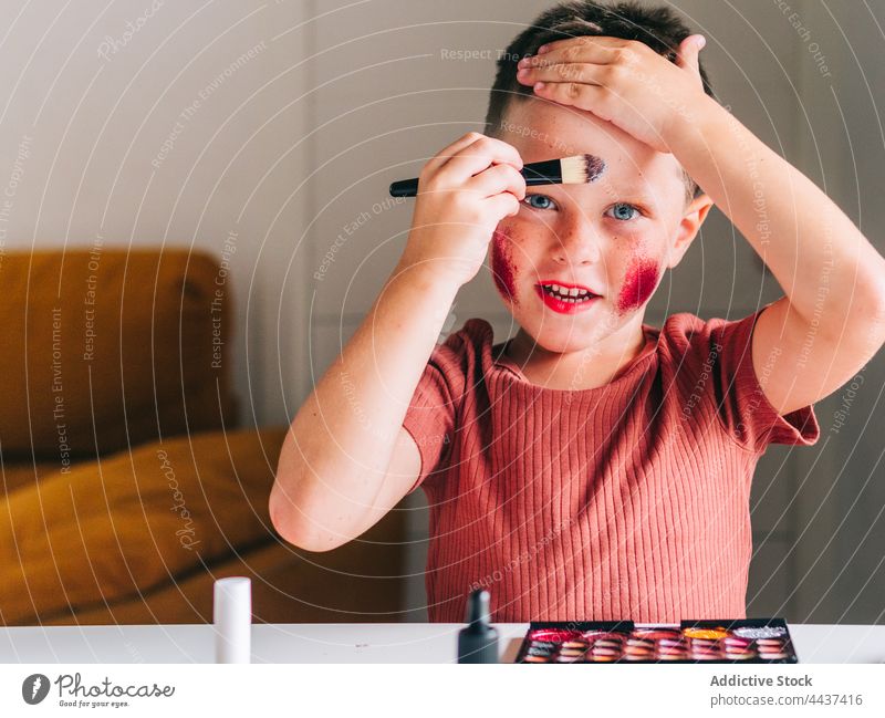 Junge trägt Lidschatten auf Gesicht in Haus Zimmer Make-up Applikator Schönheit Kosmetik Tastkopf dekorativ unordentlich Spaß haben Porträt Kindheit Palette