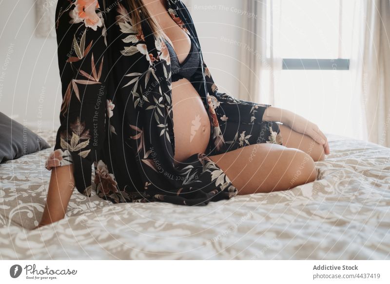 Anonyme schwangere Frau in Unterwäsche, die sich zu Hause auf dem Bett ausruht vorwegnehmen mütterlich erwarten Windstille Dessous heimwärts Schwangerschaft