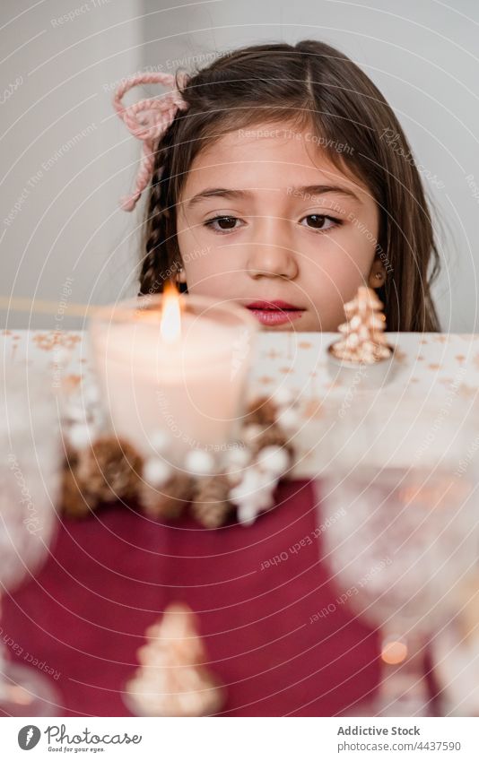 Sanftes Mädchen bewundert die brennende Kerze am Weihnachtstag nachdenken Wunsch Brandwunde Weihnachten Neujahr feiern Zauberei u. Magie festlich heimwärts