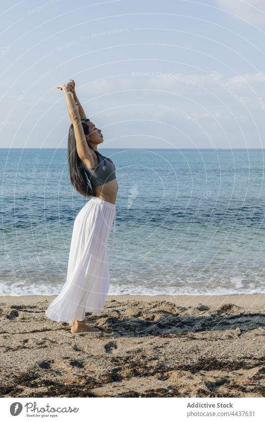 Asiatische Frau mit erhobenen Armen, die sich am Meeresufer streckt Dehnung Arme hochgezogen Yoga Gesunder Lebensstil Knöchel knacken Wellness Vitalität Energie