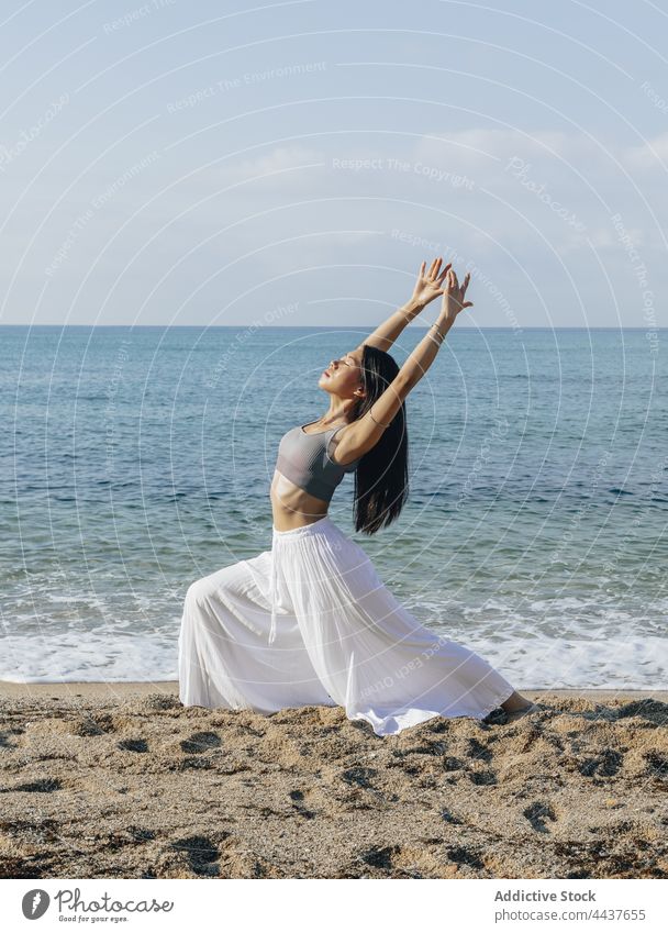 Asiatische Frau macht Crescent Lunge Pose auf Meer Strand halbmondförmiger Ausfallschritt Gleichgewicht Yoga Energie Vitalität Gesunder Lebensstil Wellness